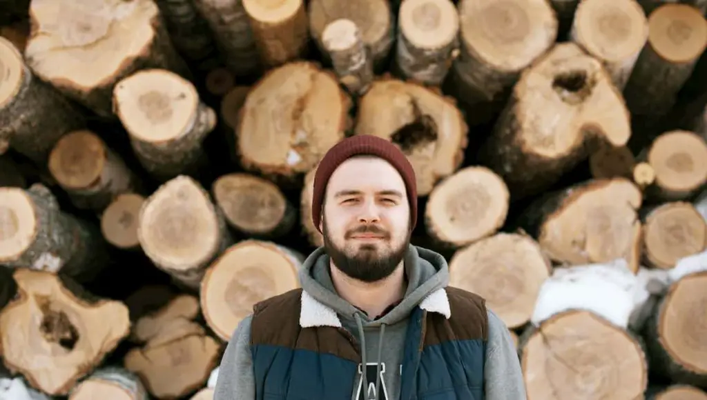 man standing in front of a pile of firewood